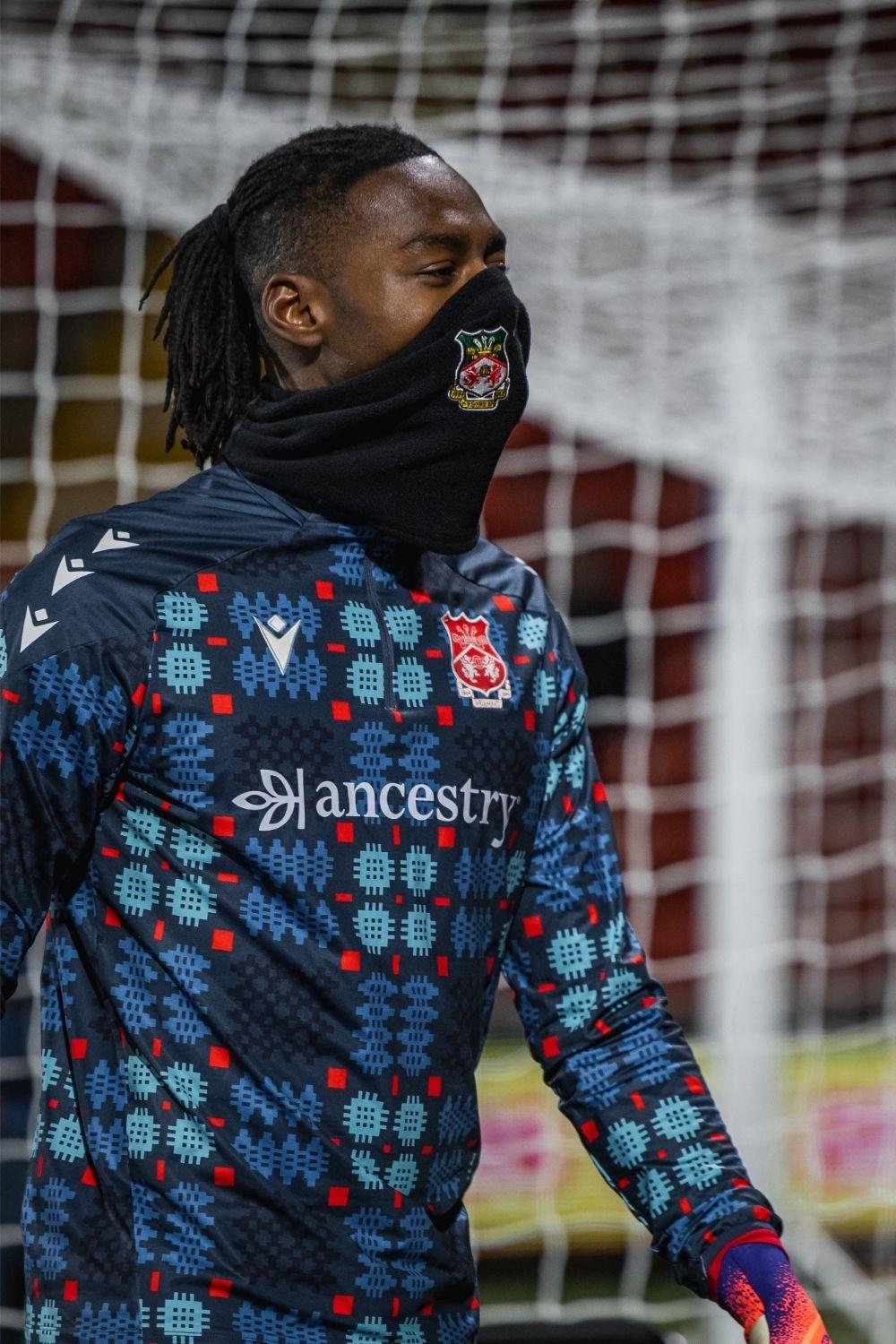Person wearing a patterned sports jacket with visible branding in front of a goal net.