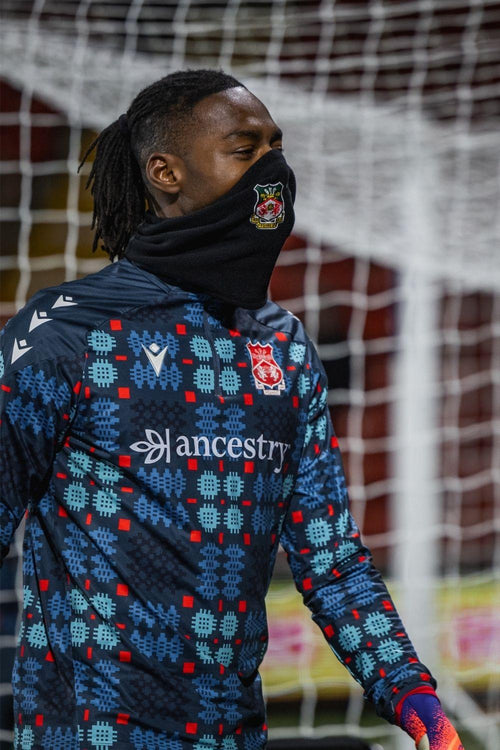 Person wearing a patterned sports jacket with visible branding in front of a goal net.
